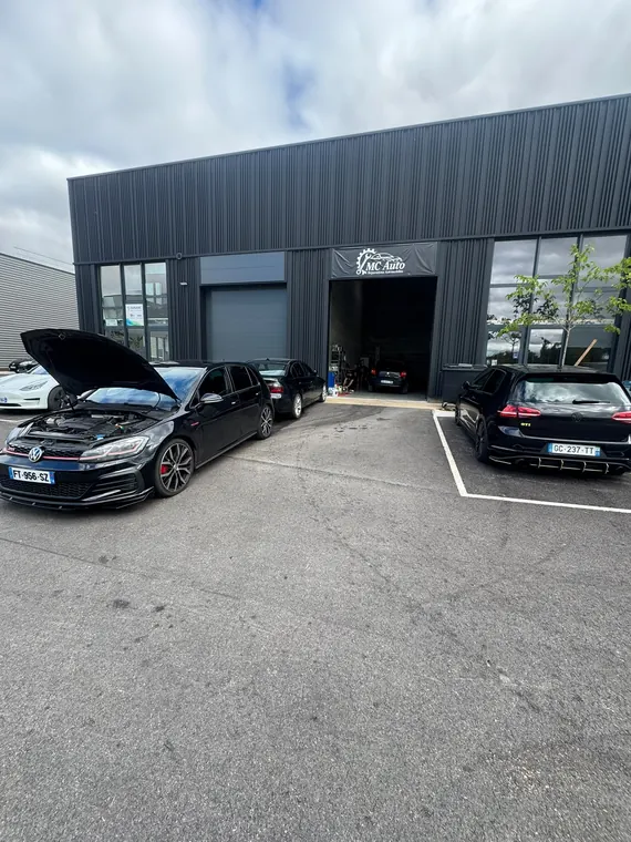 Plusieurs véhicules en attente et en cours de travaux devant l'atelier MC Auto