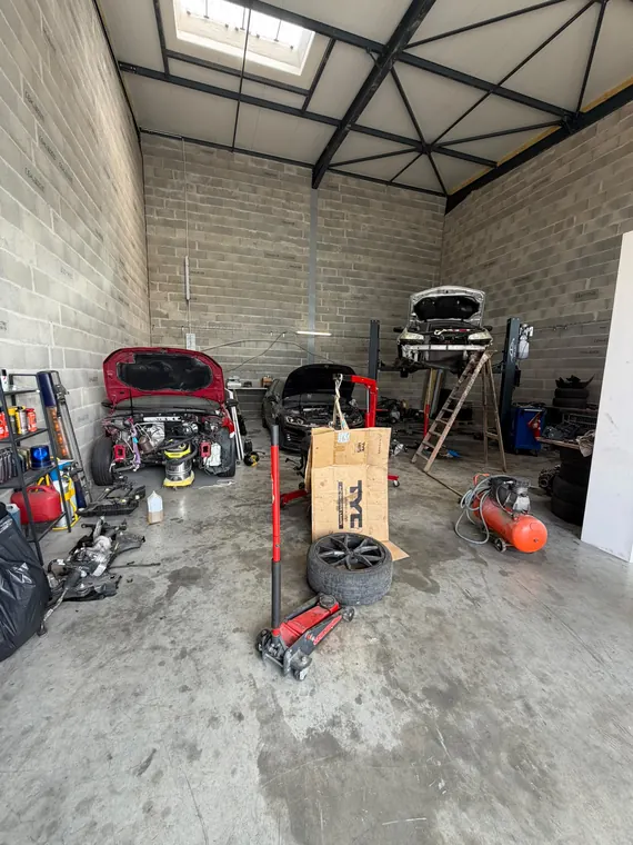Vue d'ensemble de l'atelier MC Auto avec plusieurs véhicules en cours de travaux
