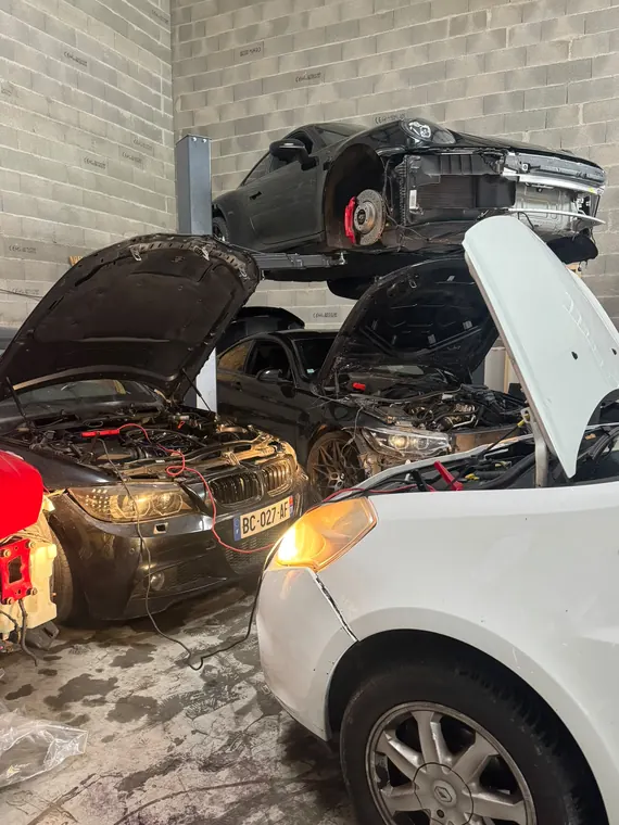 Véhicules capots ouverts et éléments avant déposés dans l'atelier MC Auto