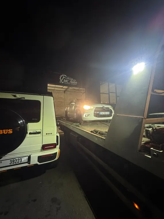 Véhicule déchargé du plateau de dépannage MC Auto de nuit, devant l'atelier