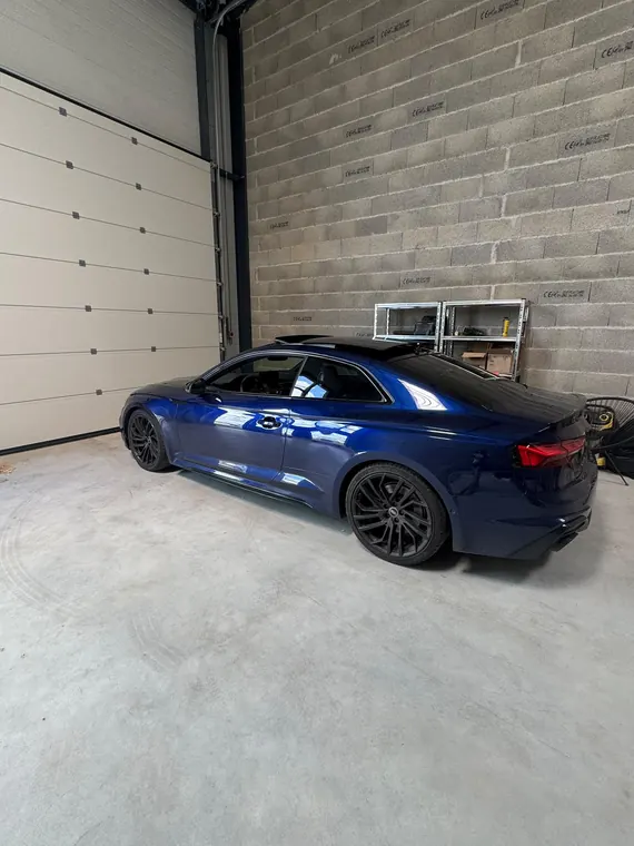 Audi RS5 bleue stationnée à l'intérieur de l'atelier MC Auto à Trévoux