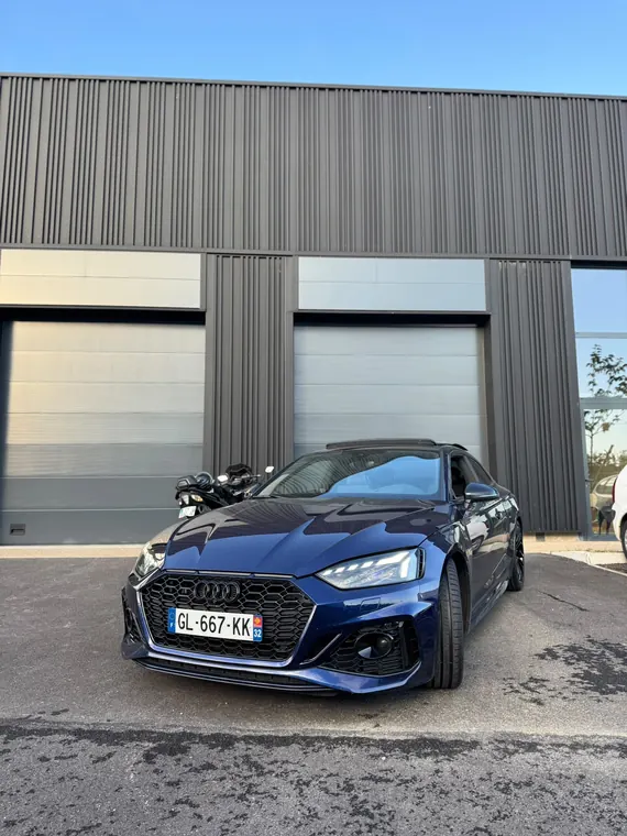 Audi RS5 bleue devant l'atelier MC Auto de Trévoux, prête à être restituée