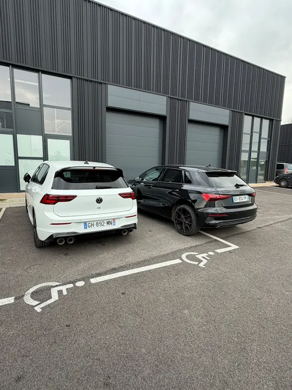 Volkswagen Golf R blanche et SUV stationnés sur le parking du garage MC Auto